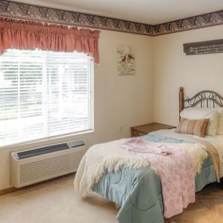 A cozy bedroom with a single bed, bedside table, and patterned trim along the ceiling.
