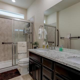 A modern bathroom with a glass-enclosed shower, double sinks, and elegant fixtures.