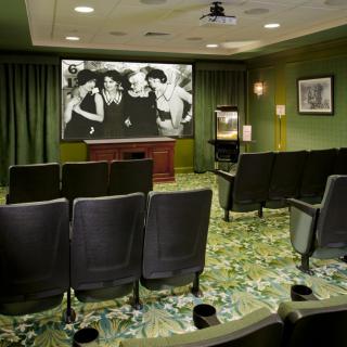 A cozy home theater setup with rows of comfortable seats facing a large projector screen.