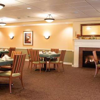 A cozy and elegant dining room with wooden tables and chairs, featuring a lit fireplace.