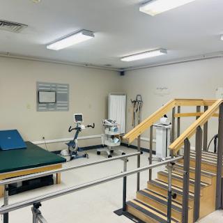 A well-equipped rehabilitation therapy room featuring exercise equipment and a staircase for patient training.
