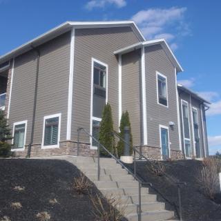 A modern residential building with a landscaped area and stairs leading up to the entrance.