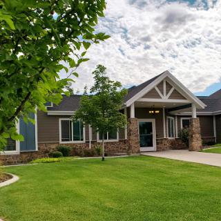A beautifully designed house set in a lush green landscape with a clear blue sky.