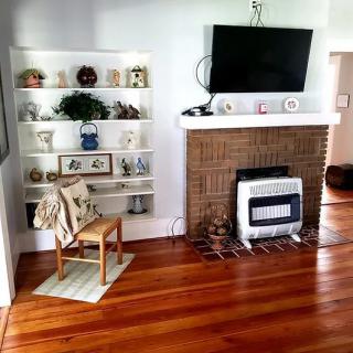Cozy living room with a fireplace, bookshelves, and wooden flooring.