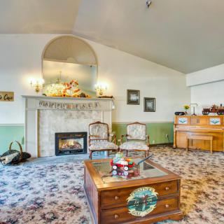 A cozy living room with vintage decor featuring a fireplace, carpeted flooring, and a piano.