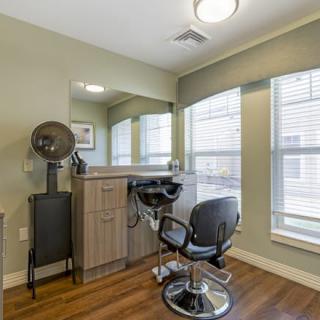 An empty hair salon with a styling chair, mirror, and hair dryer.