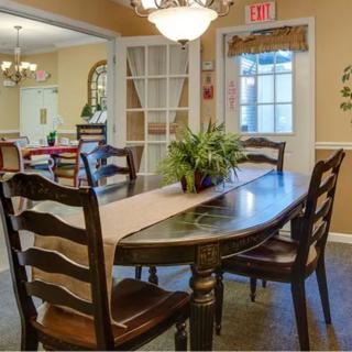 A cozy dining area featuring a wooden table and chairs, accented by a potted plant and warm lighting.