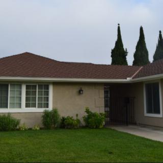 A suburban residential house with a well-maintained lawn and surrounding trees.