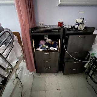A view of a hospital patient's bedside, featuring two cabinets with medical supplies.
