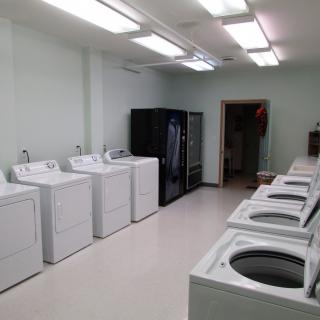 A clean and well-organized laundry room with multiple washing machines and dryers.