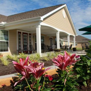 A charming house with a covered porch and landscaped garden featuring blooming flowers.