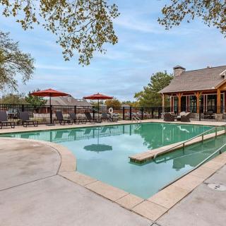 A serene outdoor pool area with chairs and umbrellas, surrounded by trees and a rustic building.