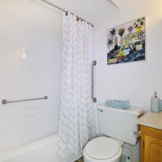 A modern bathroom featuring a bathtub with a shower curtain, a toilet, and a sink.