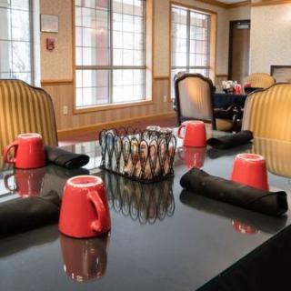 A neatly arranged dining room table with red cups and black napkins.