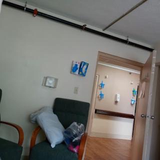 A glimpse into a hospital waiting area, featuring chairs and an adjacent doorway leading to another room.