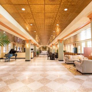 A spacious and elegant lobby featuring comfortable seating, a grand piano, and bright lighting.