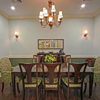 A well-decorated dining room featuring a wooden table, elegant chairs, a chandelier, and wall sconces.