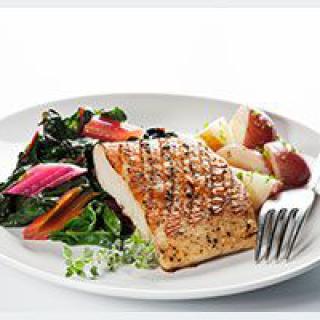 A delicious grilled fish served with colorful vegetables.
