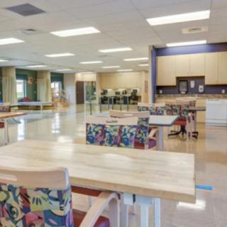 A modern open workspace with colorful chairs and a kitchenette area.