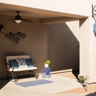 A cozy outdoor patio space featuring a sofa adorned with cushions, a decorative rug, and a playful touch of greenery.