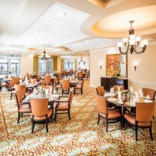 A spacious and elegantly decorated restaurant dining area with neatly arranged tables and chairs.