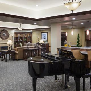 A cozy lounge featuring a grand piano, comfortable seating, and elegant lighting.