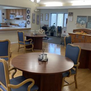 A community room with tables and chairs arranged for dining or group activities.
