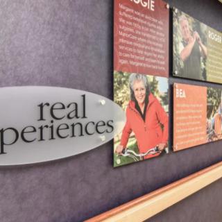 A wall exhibit featuring photographs and text, with a sign reading 'real experiences'.