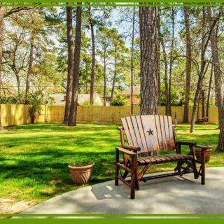 A tranquil backyard featuring a wooden bench surrounded by trees and sunlight.