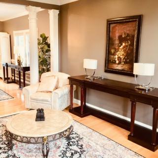 A modern living room with elegant furnishings, featuring a console table, artwork, and comfortable seating.