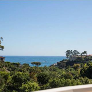 A stunning view of the coastline with lush greenery and a clear blue sky.