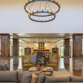 A modern living room with a large chandelier, comfortable seating, and a central fireplace.
