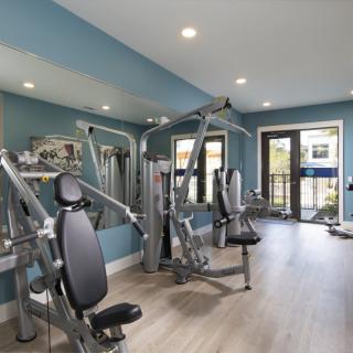 A modern gym with various exercise machines and mirrored walls.