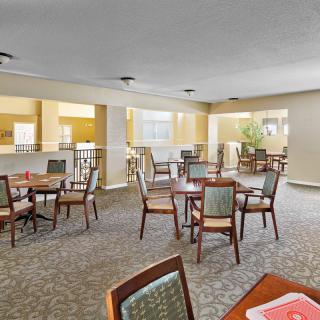 A well-lit dining area with multiple tables and chairs arranged on a carpeted floor.