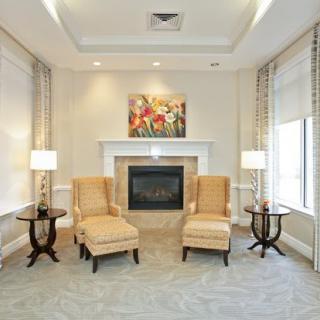 A cozy living room with a fireplace, elegant armchairs, and ambient lighting.