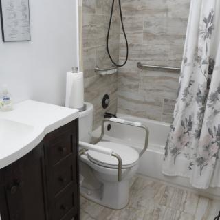 A modern bathroom featuring an accessible design with grab bars and a shower equipped for safety.