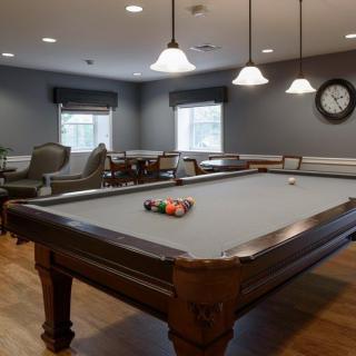 A cozy game room featuring a billiards table, comfortable seating, and warm lighting.