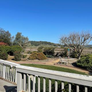 A beautiful garden view from a deck with clear blue skies and distant hills.
