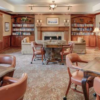 A cozy library interior with bookshelves, a fireplace, and comfortable seating.