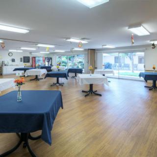 A spacious dining area with neatly arranged tables and chairs, decorated with tablecloths and flowers.