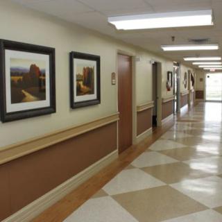A well-lit hallway with framed pictures on the walls and a tiled floor.