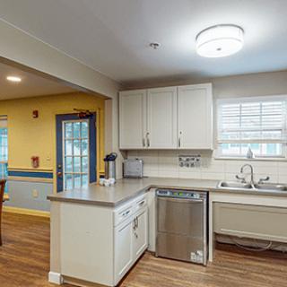 A modern kitchen with white cabinets, a stainless steel dishwasher, and a large window.