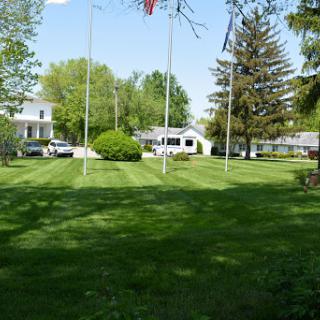 A serene outdoor scene featuring well-maintained lawns, trees, and residential buildings under a clear blue sky.