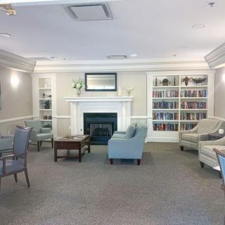 A cozy living room with a fireplace, surrounded by bookshelves and comfortable seating.