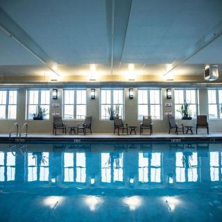 An indoor swimming pool with large windows and seating along the edges, reflecting the ambient lighting.