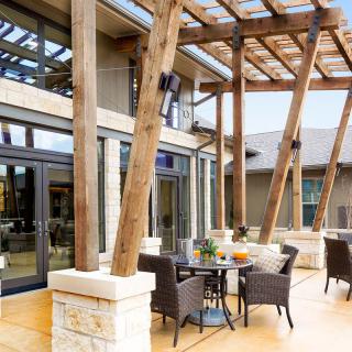 A modern outdoor patio with a wooden beam pergola and wicker furniture set on a spacious deck.