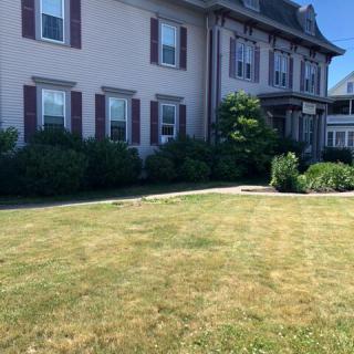 A large residential house with a well-maintained lawn on a sunny day.