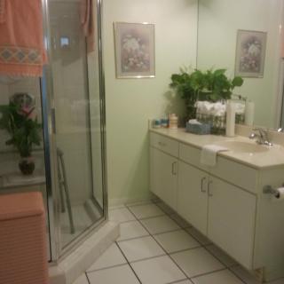 A neat bathroom featuring a glass shower, a vanity with a large mirror, and decorative plants.