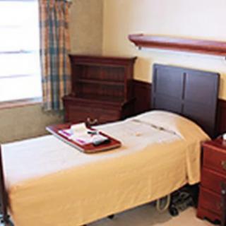 A hospital room featuring a single bed with a tray and medical equipment.