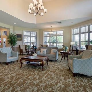 A spacious and elegantly furnished living room featuring a chandelier, comfortable sofas, and large windows.